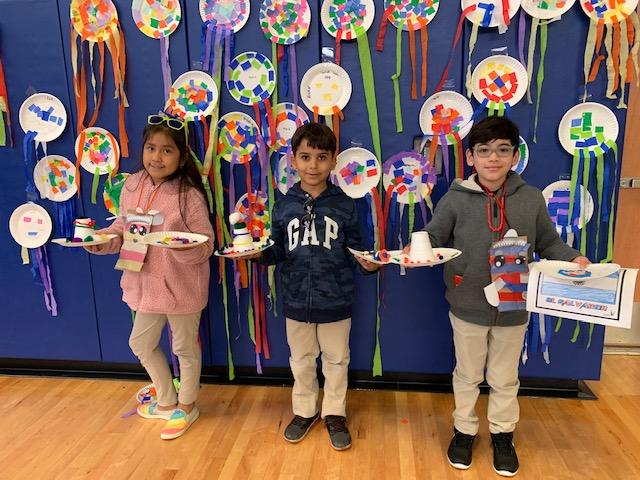 three kids showing off their finished products of puppets and kites