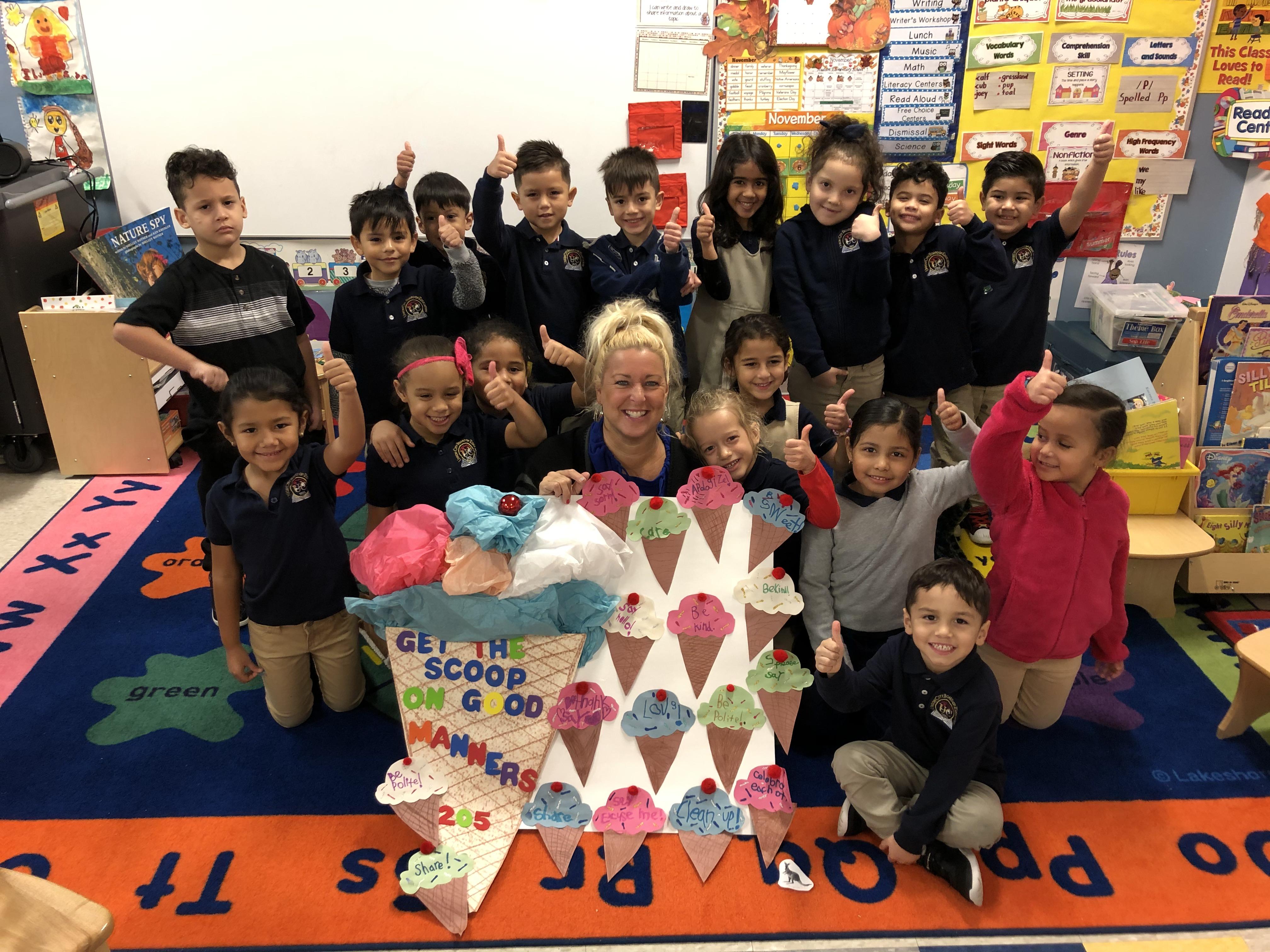 Ms. Hennesy's class holding a large student created ice cream cone with scoops of how students show respect with thumbs up