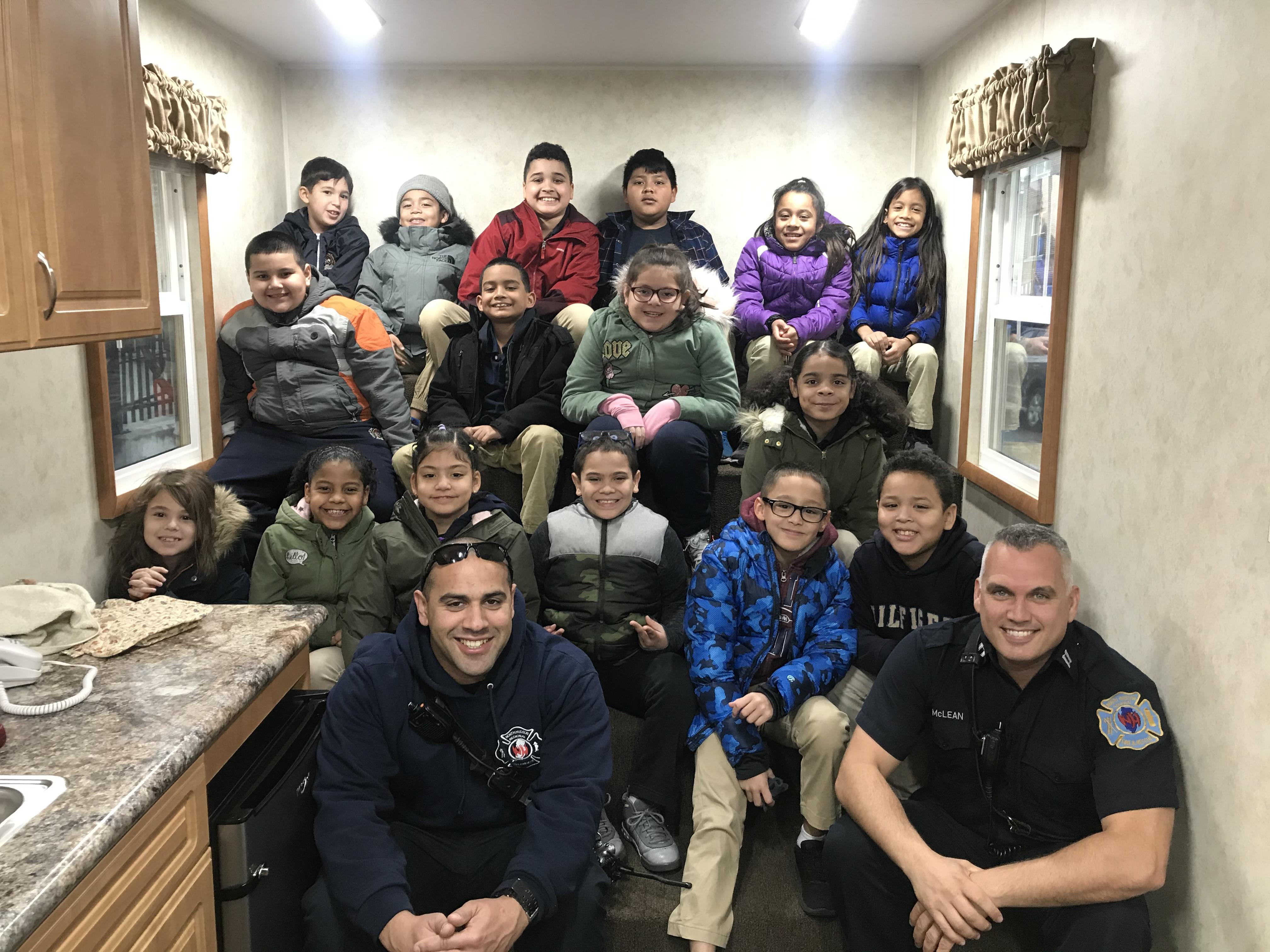 class poses with the two firefighters inside the fire safety house