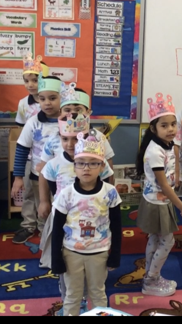 group of kids wearing crowns and t-shirt with their handprints in a straight row