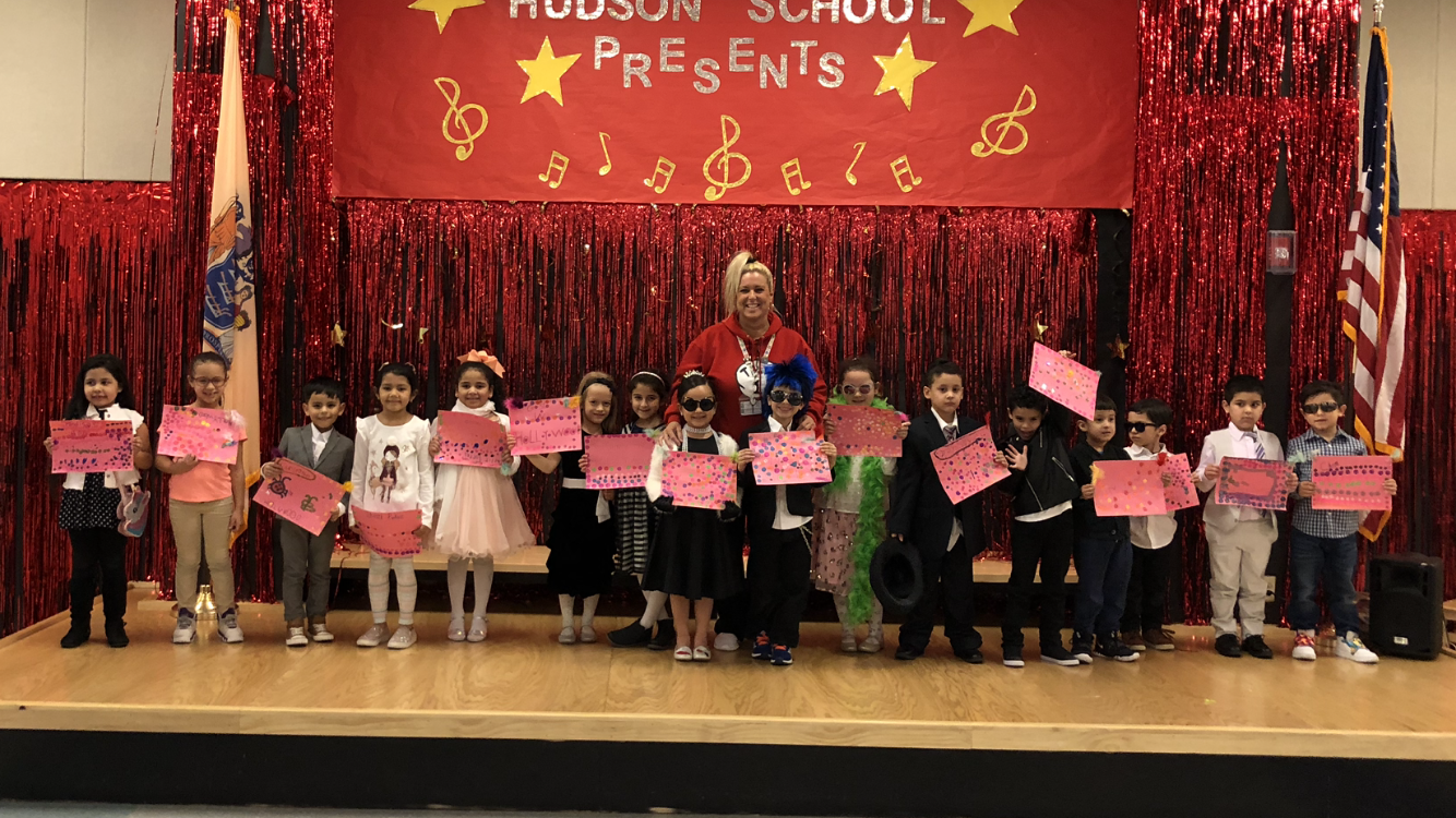Kindergartners dressed as their favorite book characters on stage with their teacher